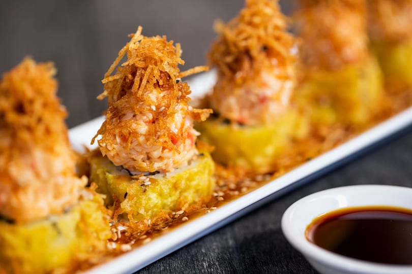 Four crispy, golden-fried sushi rolls topped with spicy crab and crunchy fried potato strings.